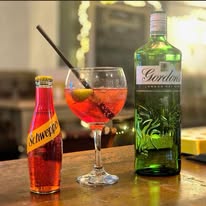 A gin and tonic garnished with cherry and pepper served at the bar